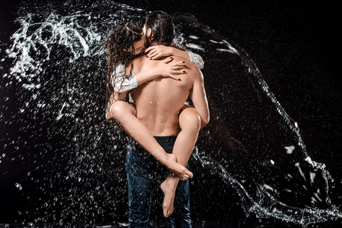 Couple embracing in a shower with water splashing, showcasing a romantic and artistic bathroom design.