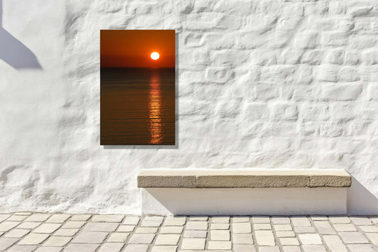 Golden Silence sunset artwork displayed on a white wall, creating a serene atmosphere in an outdoor space.
